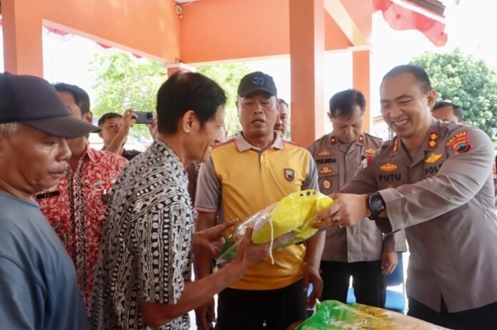 Kapolres Tegalkota AKBP I Putu Bagus Krisna Purnama (kanan) menyerahkan beras ke warga.
