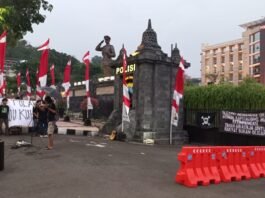 Pendemo yang memasang bendera One Piece di pagar Polda Jateng