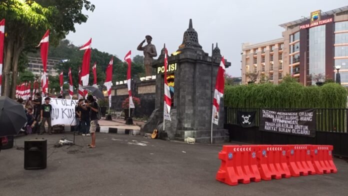 Pendemo yang memasang bendera One Piece di pagar Polda Jateng