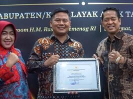 Bupati Tegal Ischak Maulana Rohman berada di tengah menunjukan piagam penghargaan