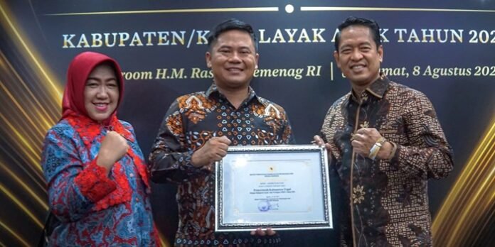 Bupati Tegal Ischak Maulana Rohman berada di tengah menunjukan piagam penghargaan