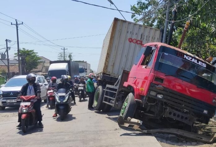 Truk tronton merah terperosok ke parit. (Foto : Sam)