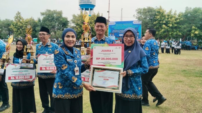 Dyah Kartika Permanasari menyerahkan sertifikat dan trophy kepada Kepala Desa Peron Erna Hermawati dalam ajang kompetisi Lomba Desa dan Kelurahan Bersih Tahun 2025, Senin (1/12/25). (Foto : Arif)