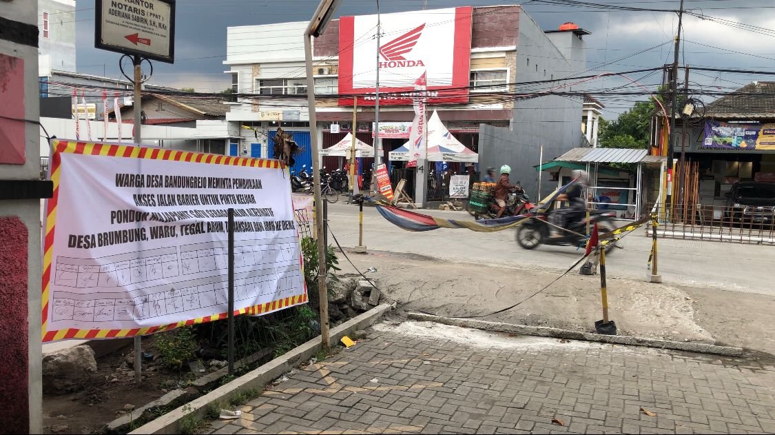 Demak Spanduk berisi tanda tangan warga dipasang di akses jalan Pondok Majapahit I, Bandungrejo, sebagai bentuk penolakan pemasangan barrier yang dinilai menghambat mobilitas masyarakat. (Foto:Sam)