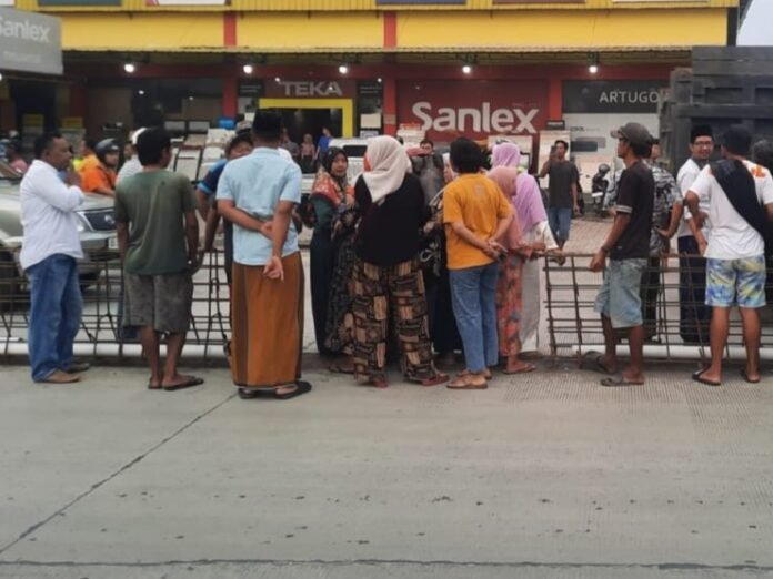 Warga Bandungrejo berkumpul di depan pagar pembatas saat menyampaikan protes terkait akses jalan menuju makam yang dianggap terlalu sempit. (Foto:Sam)