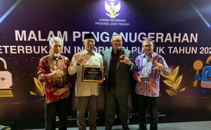 Plt Kadinkominfo Demak Umar Surya Suksmana menerima penghargaan Kabupaten Informatif 2025, didampingi Direktur RSUD Sunan Kalijaga dan jajaran Kominfo. (Foto:Sam)
