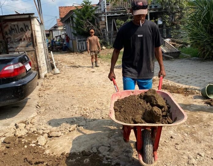 Warga Dukuh Gebang Buntu bergotong royong menguruk jalan yang kerap tergenang air, Kamis (25/12/2025). (Foto: Sam)