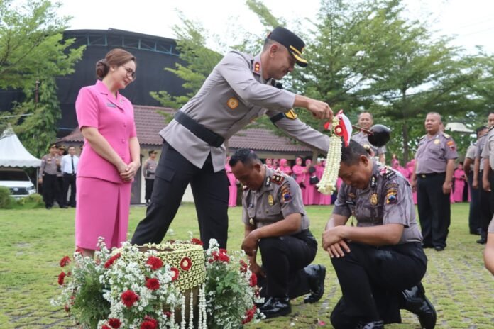 Kapolres Demak mengenakan tanda kenaikan pangkat kepada personel dalam upacara resmi dan disaksikan jajaran anggota dan Bhayangkari di Lapangan Wicaksana Laghawa, Rabu (31/12/2025). (Foto : Sam)
