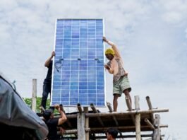 Mak Jah berpose di depan instalasi panel surya yang baru terpasang di rumahnya di Dukuh Senik, Desa Bedono, Sayung, Demak, setelah tiga tahun hidup tanpa akses listrik akibat banjir rob. (Foto:Sam)