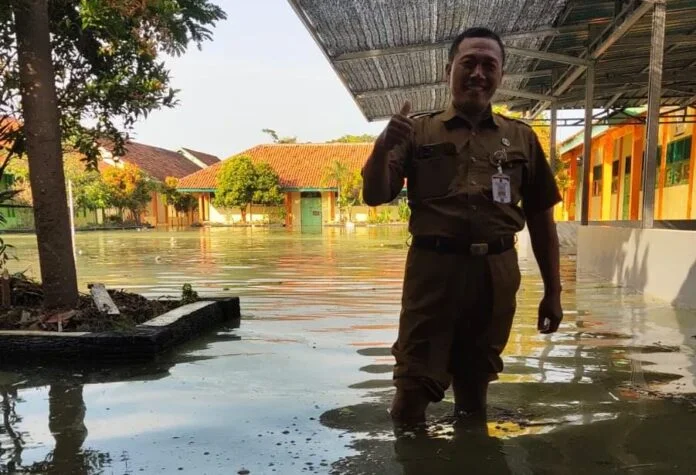 Kepala SMPN 3 Bonang, Hery Sarwanto, meninjau langsung kondisi halaman sekolah yang terendam banjir setinggi sekitar 50 sentimeter, Selasa (6/1/2026). (Foto:Sam)