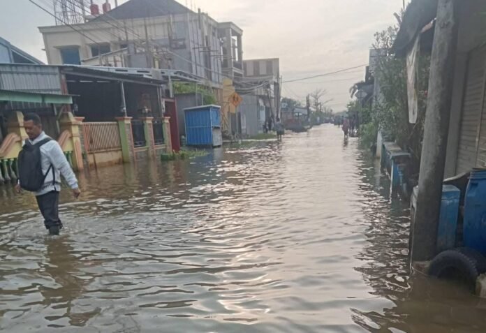 Warga melintas di jalan raya Demak-Bonang di Desa Tridonorejo, Kecamatan Bonang, Demak, yang terendam banjir rob bercampur hujan. Ketinggian air dilaporkan terus meningkat dan menggenangi rumah warga. (Foto:Sam)