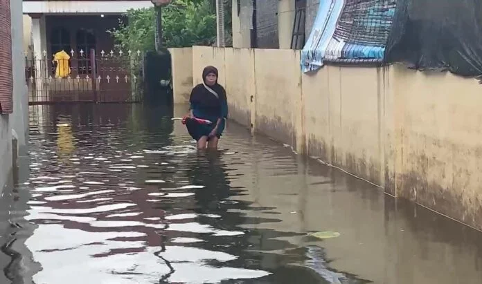 Warga melintasi genangan banjir yang merendam permukiman di Desa Wonorejo, Kecamatan Karanganyar, Demak, akibat hujan deras dan buruknya aliran air, Rabu (14/1/2026). (Foto:Sam)