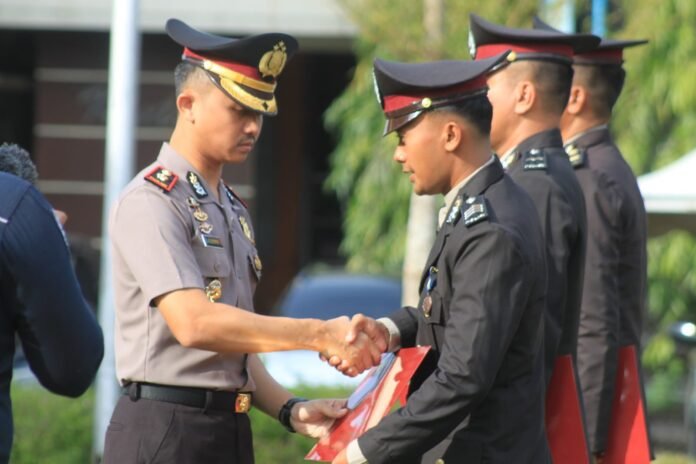 Wakapolres Demak Kompol Hendrie Suryo Liquisasono menyematkan Tanda Kehormatan Satya Lencana kepada personel Polres Demak dalam upacara penghargaan atas pengabdian tanpa pelanggaran di Mapolres Demak, Senin (26/1/2026). (Foto:Sam)