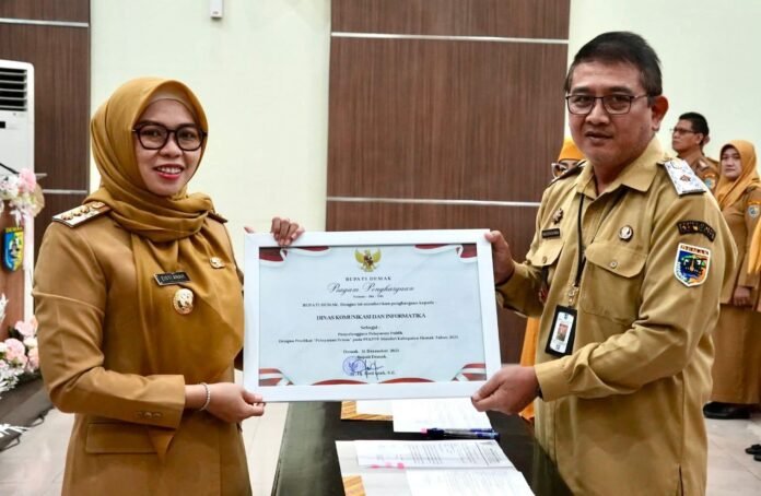 Bupati Demak Eisti’anah menyerahkan Piagam Penghargaan PEKPPP Mandiri Tahun 2025 kepada Plt. Kepala Dinas Komunikasi dan Informatika Kabupaten Demak, Umar Surya Suksmana, di Gedung Gradhika Bina Praja. (Foto:Sam)