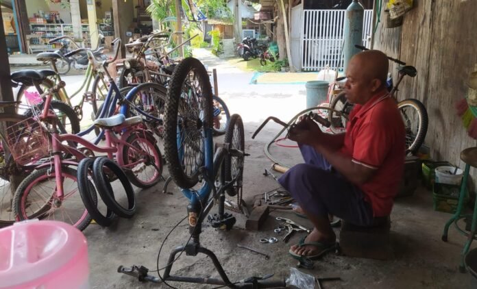 Purnadi, tukang servis sepeda di Desa Bumiharjo, Kecamatan Guntur, Demak, tengah memperbaiki sepeda klasik milik pelanggan. Meski hampir berusia 59 tahun, keahliannya merawat sepeda onthel hingga modern tetap menjadi andalan para kolektor dan komunitas sepeda tua. (Foto:Sam)