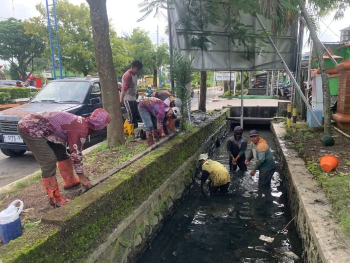 Petugas Dinputaru Kabupaten Demak melakukan pembersihan drainase secara manual di sepanjang Jalan Sultan Fatah hingga Terminal Demak sebagai upaya mencegah banjir dan menjaga kebersihan lingkungan perkotaan, Jumat (13/2/2026). (Foto:Sam)