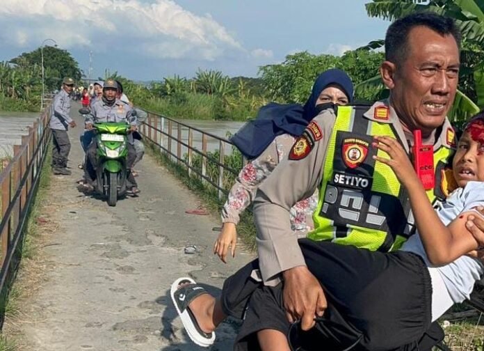 Anggota polisi berlari panik sambil menggendong seorang bocah dengan kepala berlumuran darah. (Foto : Sam)