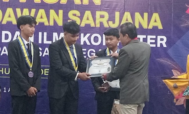 WhatsApp Image 2026-04-01 at 14.24.01 Dekan FTIK UPS Dr. Agus Wibowo saat menyerahkan penghargaan wisudawan