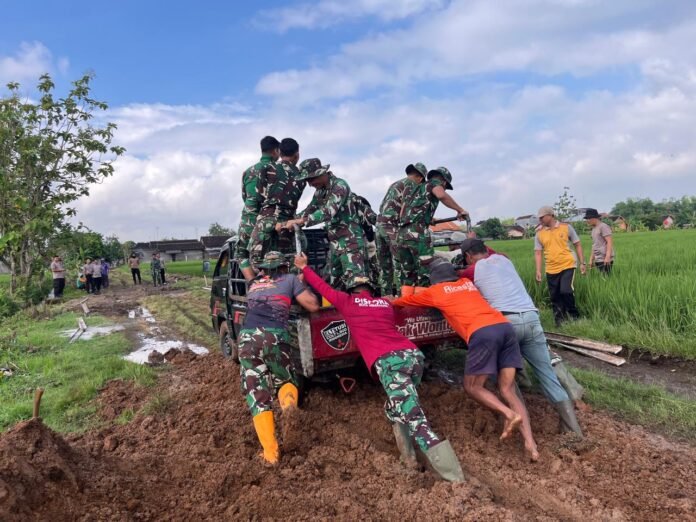 Masyarakat desa Puro bersama anggota Satgas TMMD ke-128 Kodim 0725/Sragen, bahu membahu membantu mendorong mobil pembawa matrial yang selip. (Foto : Dok TMMD Sragen)