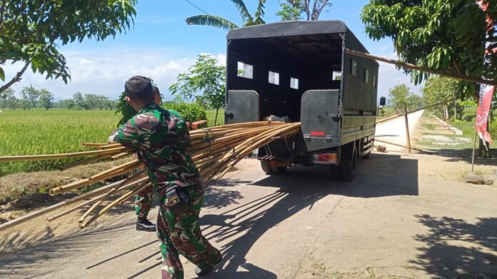 Ketua Kelompok Tata Usaha dan Urusan Dalam (Kapok Tuud) Serma Ngatiman bersama anggota Satgas lainnya tampak sibuk mendroping bambu untuk persiapan pemasangan umbul-umbul penutupan TMMD. (Foto : Dok TMMD Sragen)