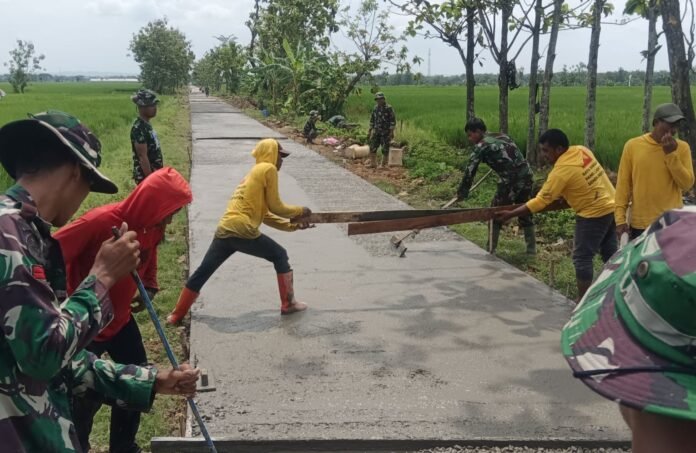 Anggota Satgas TMMD Reg ke-128 Kodim 0725/Sragen dengan warga semangat melanjutkan pekerjaan pengecoran jalan Minggu (03/05/2026). (Foto : Dok TMMD Sragen)