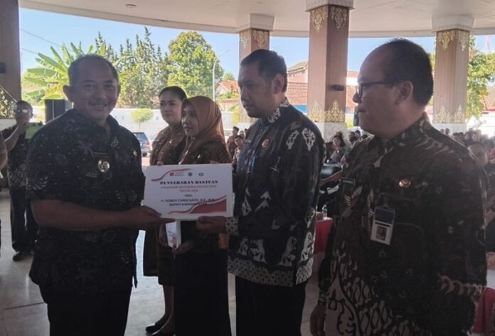 Bupati Karanganyar Rober Christanto menyerahkan PIP kepada perwakilan kepala sekolah. (Foto: Iwan).