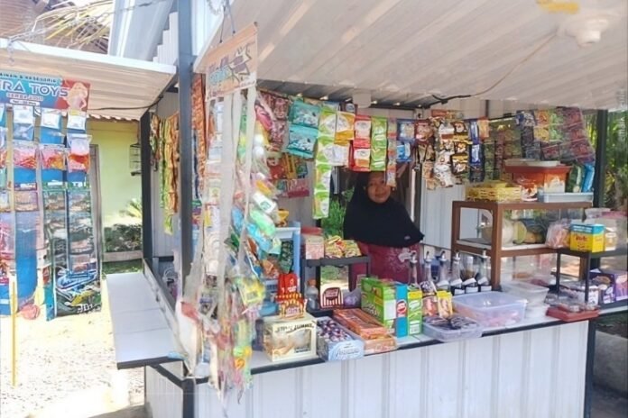 Qomidatul Rifa’ah atau Bu Ida melayani usaha warung kecil miliknya di Desa Kaliaman, Kecamatan Kembang, Kabupaten Jepara. YBM PLN UIK Tanjung Jati B menyalurkan bantuan modal usaha dan paket sembako kepada Bu Ida, sebagai bentuk kepedulian PLN dalam mendorong kemandirian ekonomi warga dan mendukung keberlanjutan usaha kecil masyarakat sekitar. (Foto : Dok PLN)
