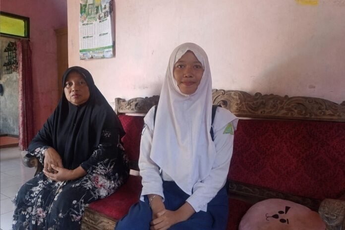 Atta Maulina bersama ibunya di kediamannya di Desa Kedungleper, Kecamatan Bangsri, Kabupaten Jepara. YBM PLN UIK Tanjung Jati B memberikan bantuan biaya tunggakan pendidikan dan paket sembako kepada Atta sebagai bentuk dukungan terhadap keberlanjutan pendidikan anak dari keluarga prasejahtera. (Foto : Dok PLN)